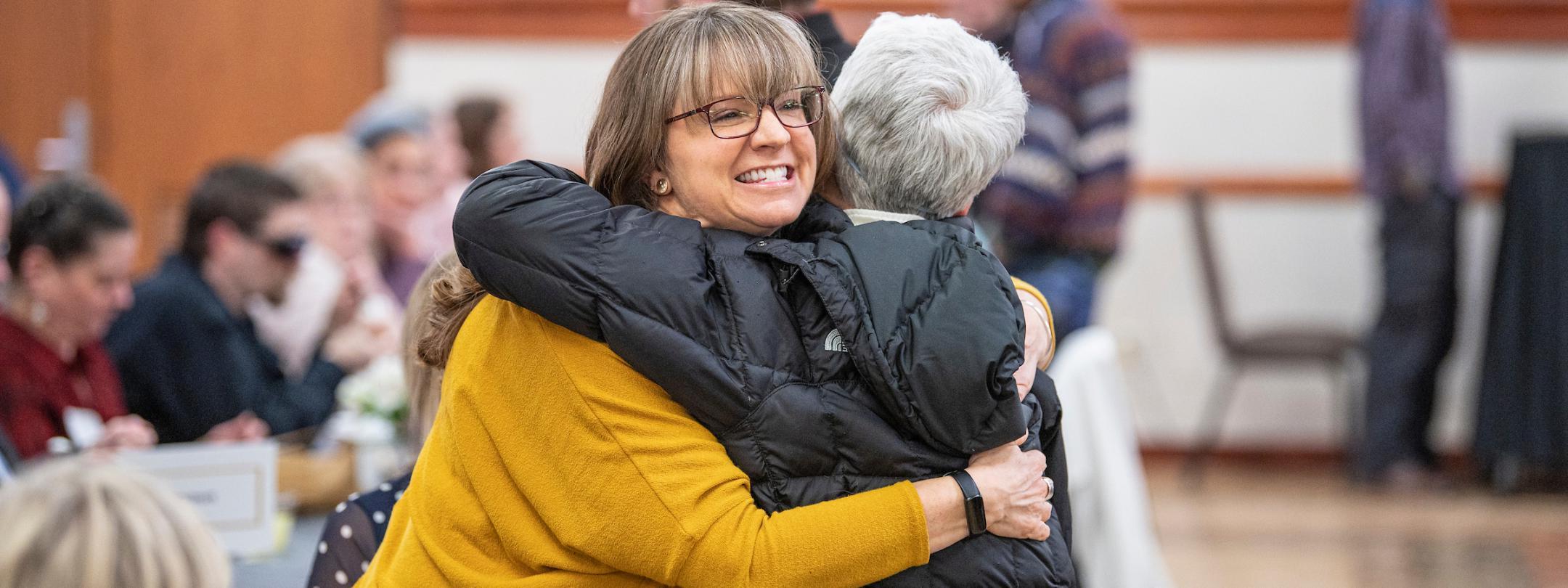 Faculty hug each other.